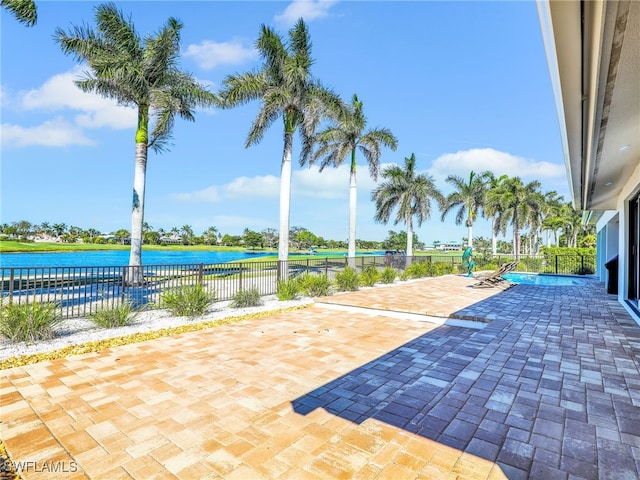 view of patio featuring fence and a water view