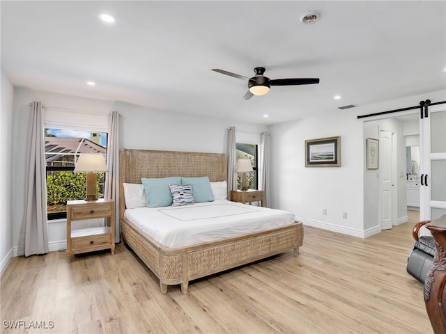 bedroom featuring light wood finished floors, visible vents, multiple windows, and a barn door