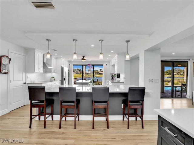 kitchen featuring visible vents, stainless steel fridge with ice dispenser, light countertops, light wood-style floors, and white cabinets