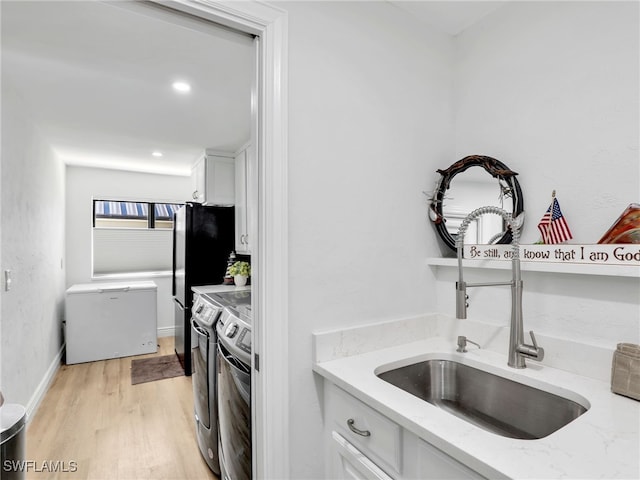 kitchen featuring light stone counters, independent washer and dryer, white cabinetry, fridge, and a sink