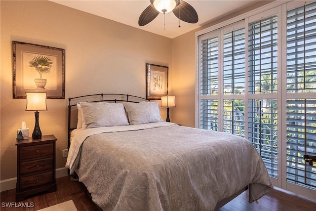 bedroom featuring multiple windows, baseboards, and wood finished floors