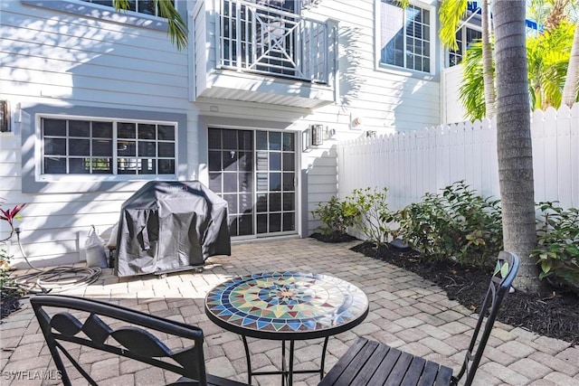 view of patio with a grill, a balcony, and fence