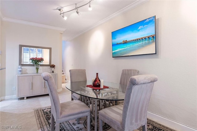 dining area with rail lighting, baseboards, and crown molding