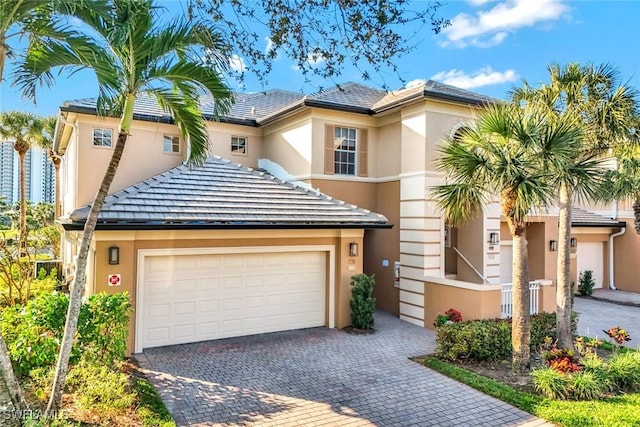 view of front of home with stucco siding, decorative driveway, and a garage