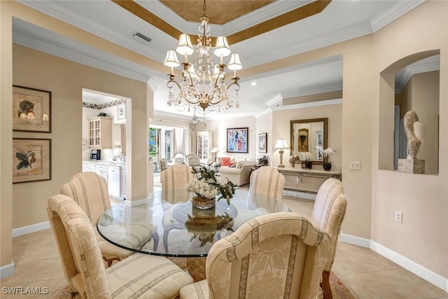 dining area with light tile patterned floors, a tray ceiling, an inviting chandelier, and ornamental molding