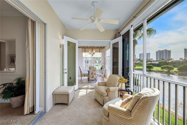 sunroom / solarium featuring a water view, a city view, and ceiling fan with notable chandelier