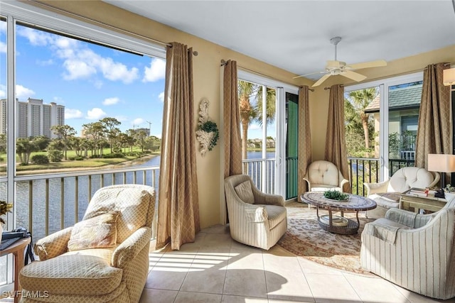 sunroom with plenty of natural light, a ceiling fan, and a water view