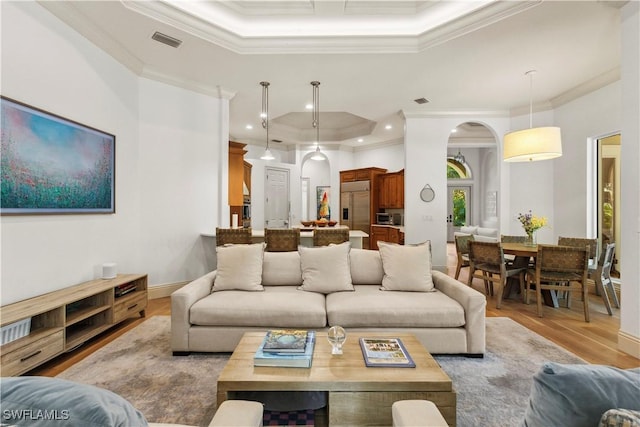 living room with a tray ceiling, crown molding, and visible vents