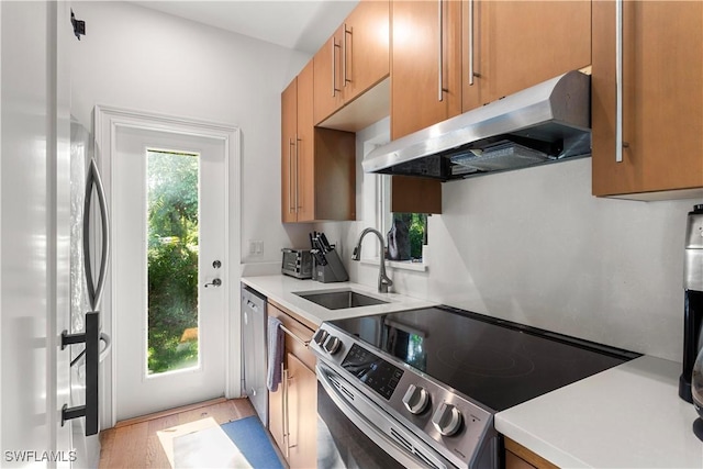 kitchen with under cabinet range hood, plenty of natural light, appliances with stainless steel finishes, and a sink