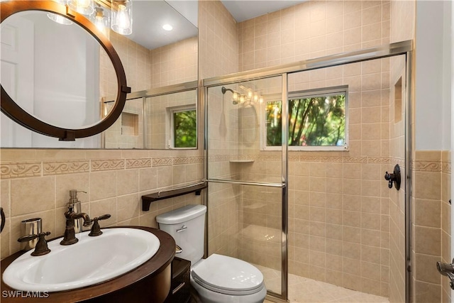 bathroom featuring toilet, tile walls, a stall shower, and vanity