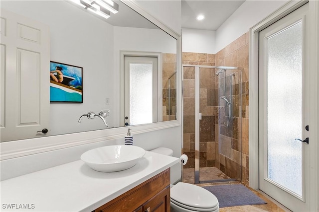 bathroom featuring vanity, a shower stall, and toilet