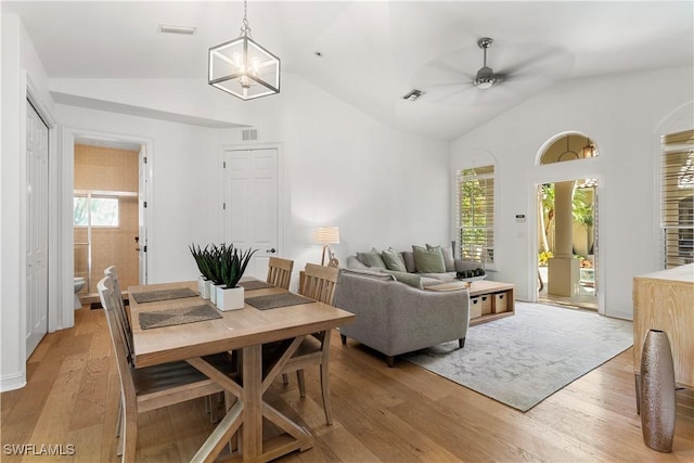 living room featuring lofted ceiling, light wood-style flooring, ceiling fan with notable chandelier, and visible vents