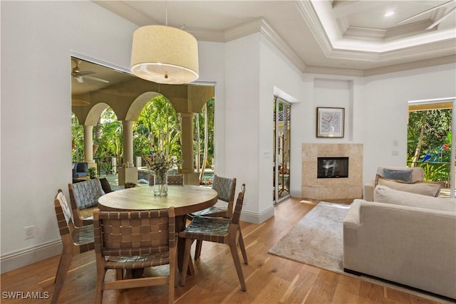 dining area featuring wood finished floors, a high ceiling, ornamental molding, and a fireplace