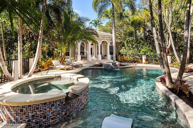 view of swimming pool with a patio area, fence, and a pool with connected hot tub