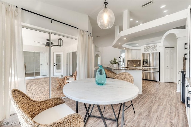 dining area with visible vents, recessed lighting, arched walkways, ceiling fan, and light wood-type flooring