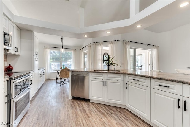 kitchen with a sink, stainless steel appliances, light wood-style flooring, and white cabinetry