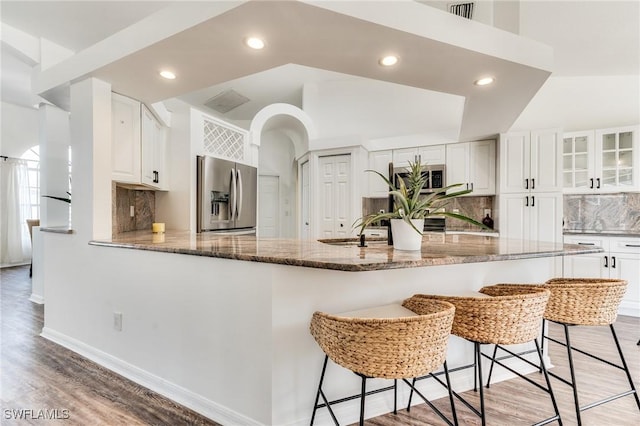 kitchen with stone countertops, light wood-style floors, appliances with stainless steel finishes, white cabinets, and glass insert cabinets