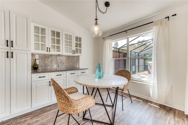 dining space with baseboards, lofted ceiling, and light wood-style floors