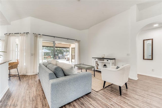 living area featuring baseboards, high vaulted ceiling, and wood finished floors