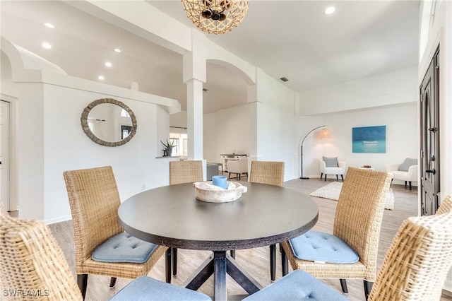 dining space with recessed lighting, wood finished floors, and arched walkways