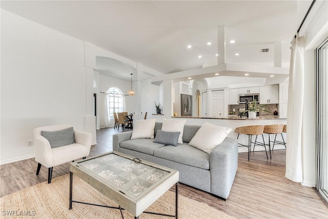 living area with light wood-type flooring, visible vents, recessed lighting, arched walkways, and lofted ceiling