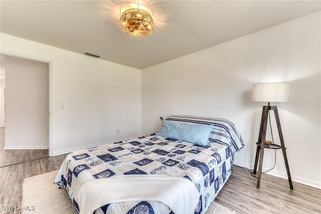 bedroom featuring visible vents, baseboards, and wood finished floors