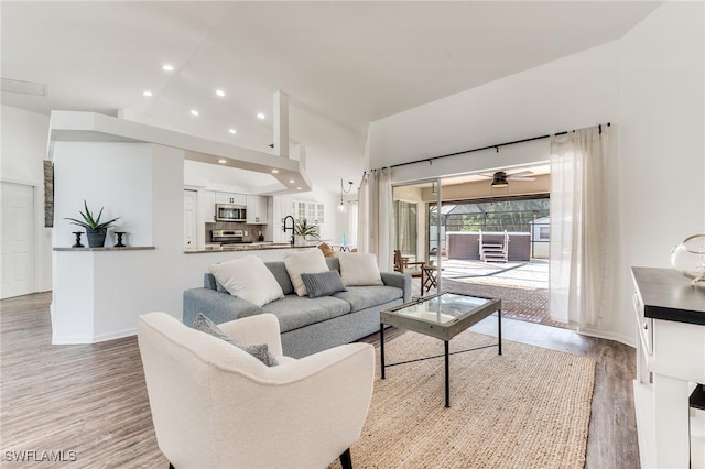 living room featuring recessed lighting, light wood-type flooring, baseboards, and lofted ceiling