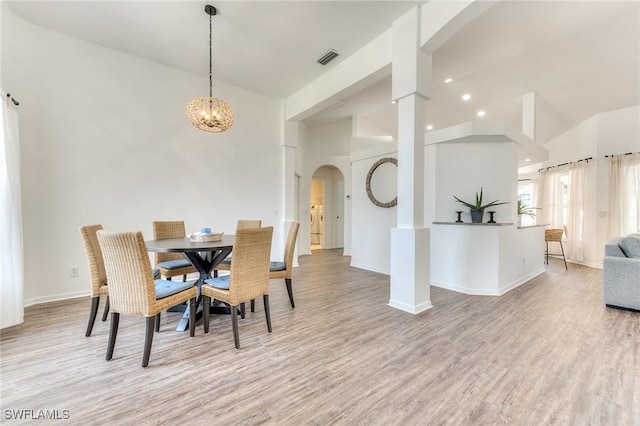 dining area featuring visible vents, light wood-style flooring, arched walkways, baseboards, and a chandelier