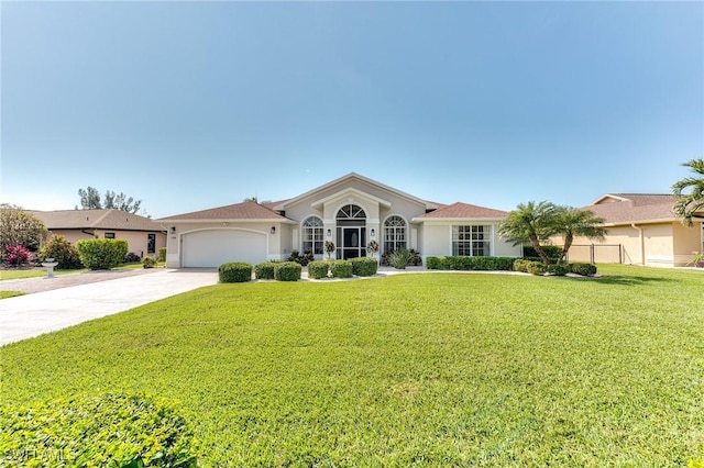 mediterranean / spanish house with a front lawn, fence, stucco siding, a garage, and driveway