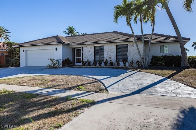 ranch-style house featuring a tile roof, an attached garage, driveway, and stucco siding