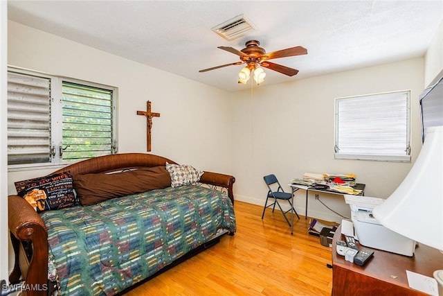 bedroom with visible vents, light wood-style flooring, baseboards, and ceiling fan