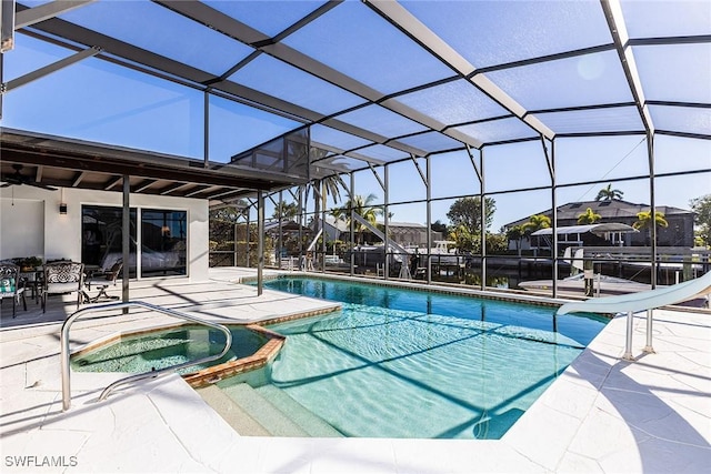 view of pool with a patio area, glass enclosure, a pool with connected hot tub, and a water slide