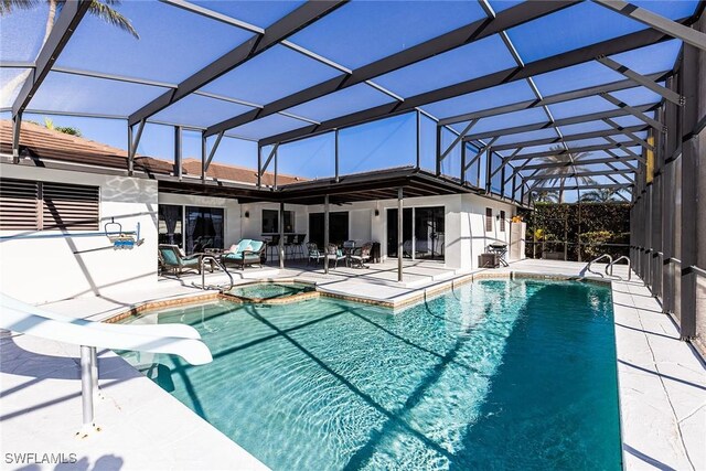 view of swimming pool featuring a patio area, a lanai, a pool with connected hot tub, and a water slide