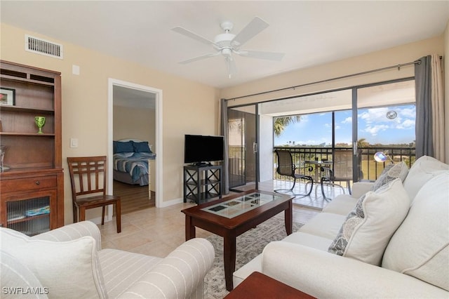 living room with light tile patterned flooring, visible vents, baseboards, and a ceiling fan