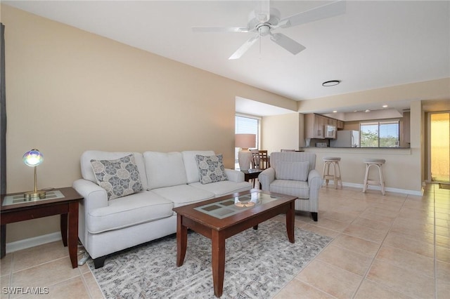 living area featuring a ceiling fan, light tile patterned flooring, and baseboards