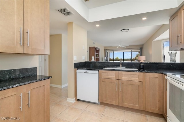 kitchen with light tile patterned flooring, a sink, dark stone countertops, white appliances, and visible vents