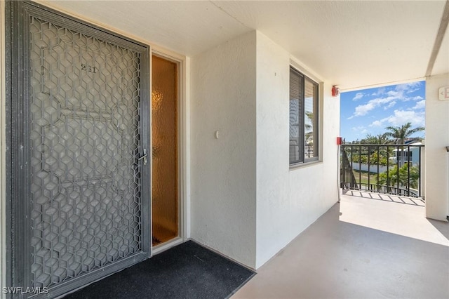 view of exterior entry featuring stucco siding and a balcony