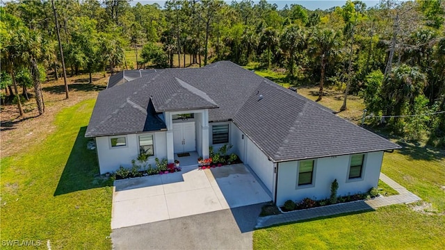 view of front of house with stucco siding, concrete driveway, and a front lawn