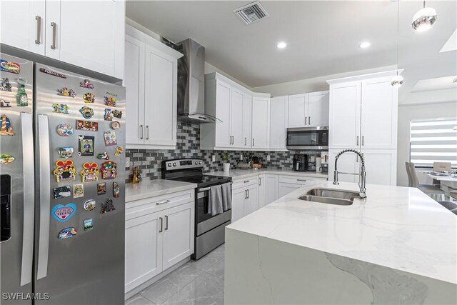 kitchen with visible vents, backsplash, wall chimney range hood, appliances with stainless steel finishes, and a sink