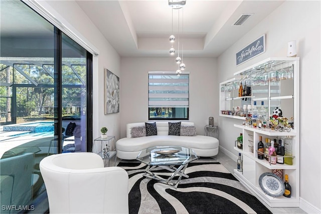 living room featuring a raised ceiling, baseboards, visible vents, and a sunroom