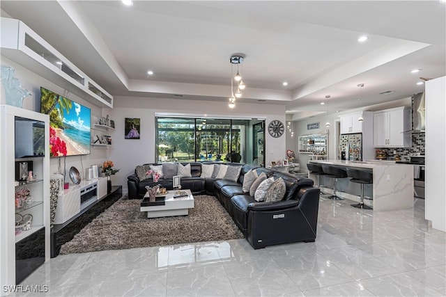 living area with marble finish floor and a tray ceiling