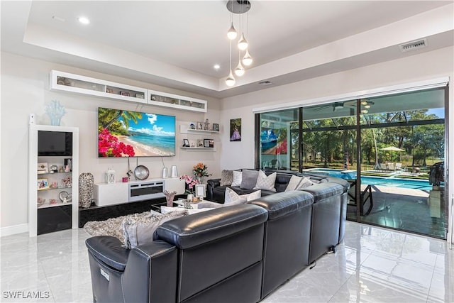 living room featuring a raised ceiling, baseboards, visible vents, and marble finish floor