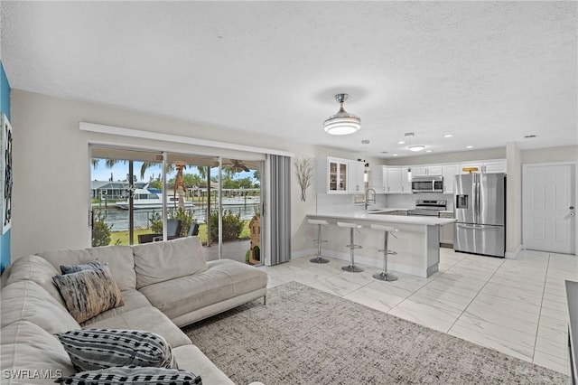 living room featuring recessed lighting, marble finish floor, a textured ceiling, and baseboards