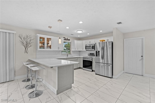 kitchen with visible vents, appliances with stainless steel finishes, a kitchen breakfast bar, a peninsula, and marble finish floor