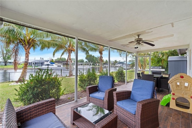 sunroom with a water view, a healthy amount of sunlight, and ceiling fan