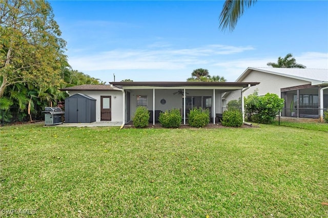 back of house with fence, a sunroom, an outdoor structure, a storage unit, and a lawn