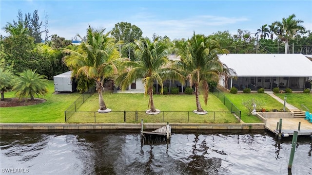 dock area featuring a yard, a water view, and a fenced backyard