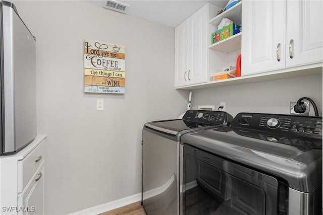 laundry room with baseboards, cabinet space, visible vents, and washing machine and clothes dryer