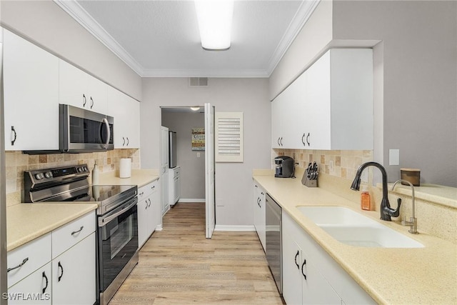 kitchen with visible vents, appliances with stainless steel finishes, crown molding, and a sink