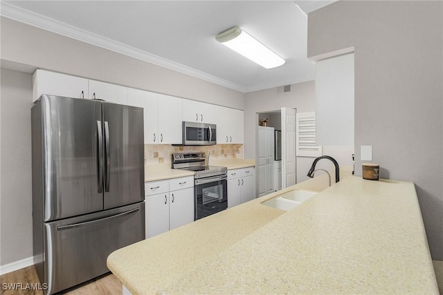 kitchen with visible vents, ornamental molding, appliances with stainless steel finishes, a peninsula, and a sink